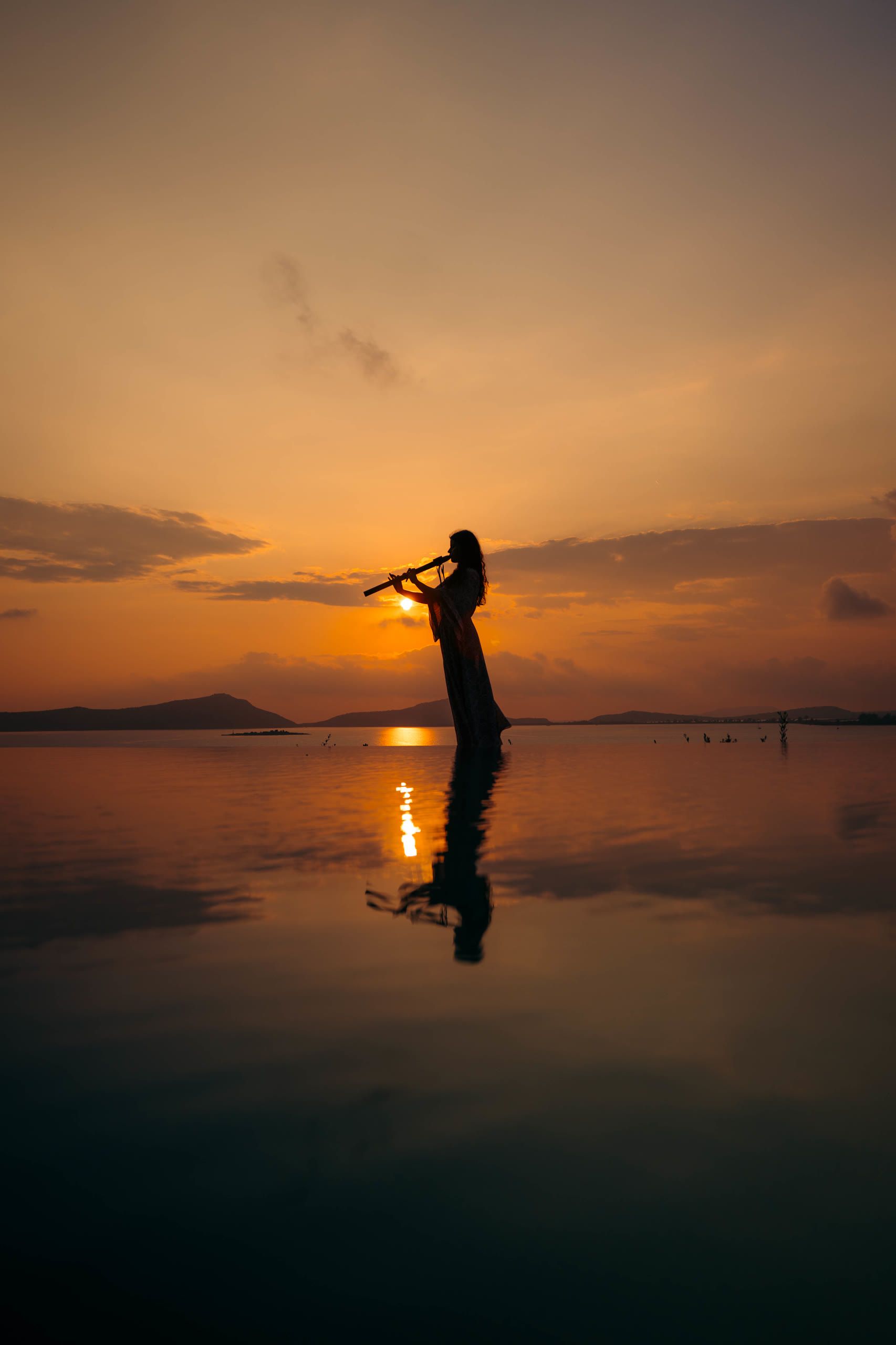 Harriet Emily playing the flute at sunset by the water
