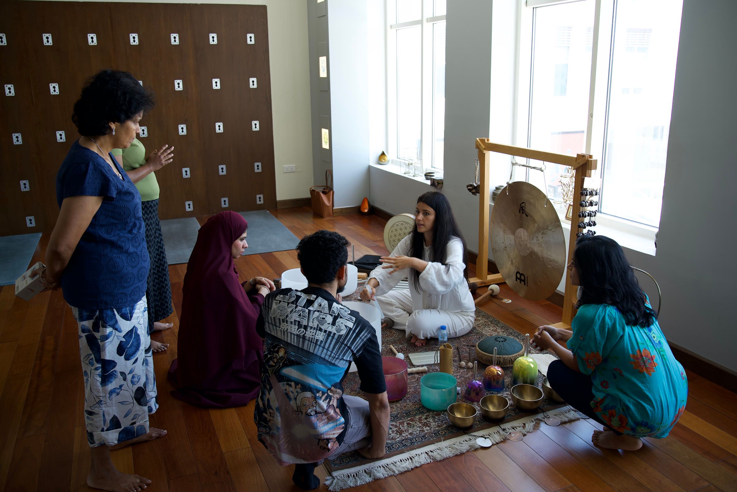 Guests gathered around Harriet Emily as she demonstrates singing bowls in a studio